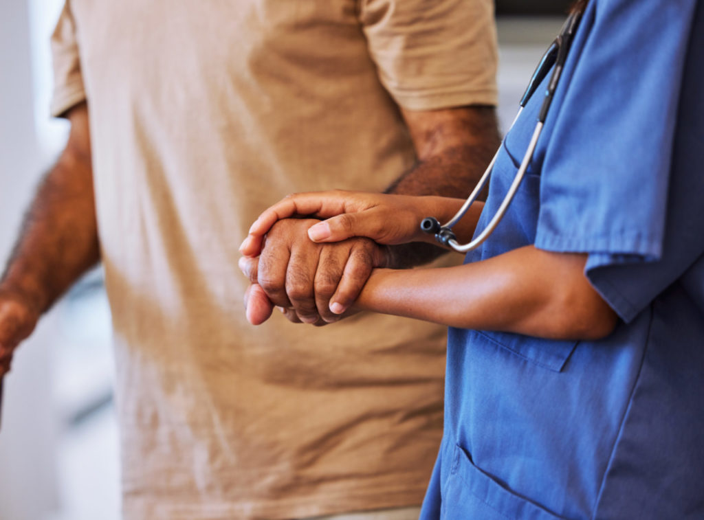 Hände eines Arztes und eines Patienten, die sich halten.